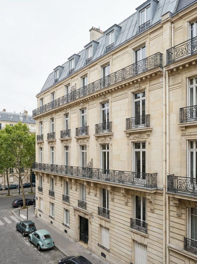 Plan appartement haussmannien : façade élégante d’immeuble parisien avec balcons en fer forgé et rues pavées.
